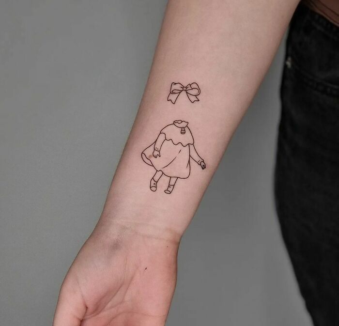 Minimalist wrist tattoo of a floating dress and bow design on forearm.