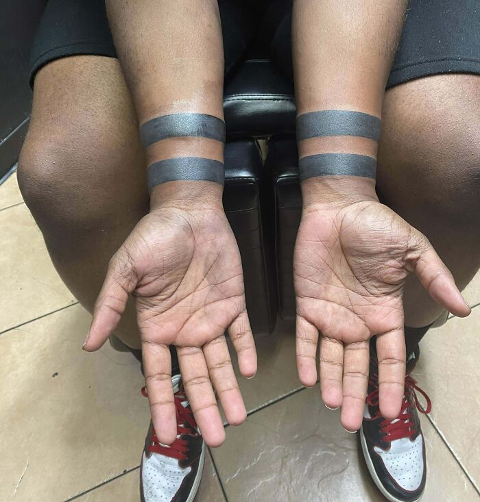 Hands showing wrist tattoo designs with bold black bands, highlighting trendy wrist tattoos.