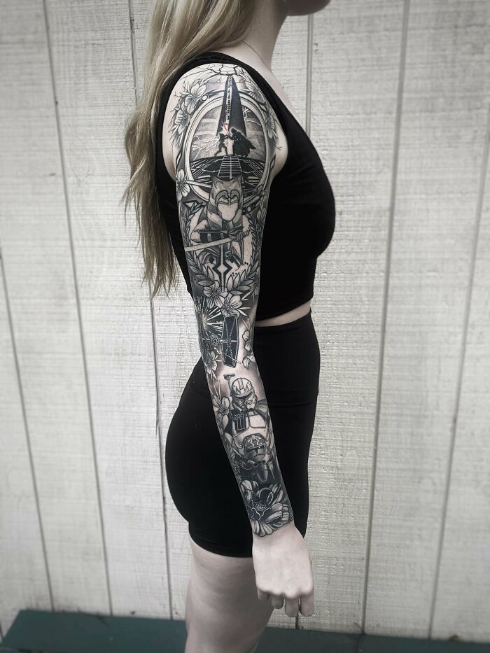 Arm with detailed pop culture tattoo sleeve featuring iconic characters and floral designs.