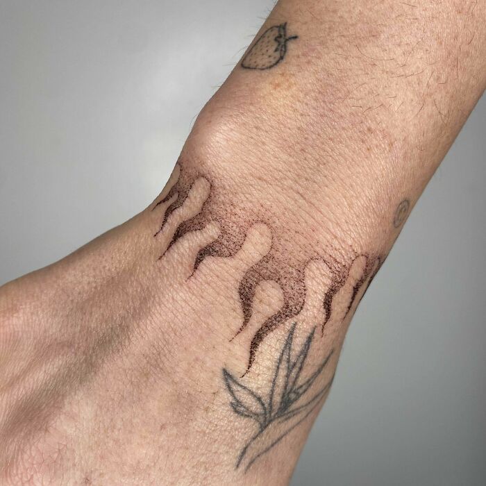 Wrist tattoo with flame and leaf designs, showcasing unique tattoo art on the wrist.