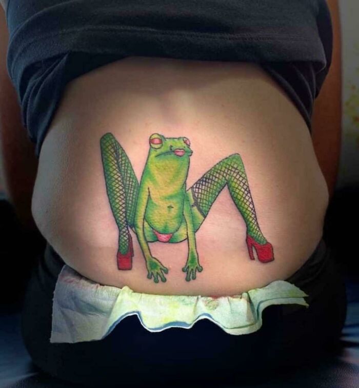 Green frog tattoo in fishnet stockings and red heels on lower back, showcasing unique tattoo ideas.