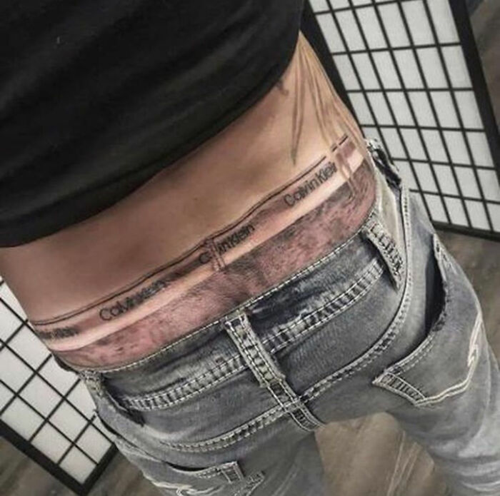 Tattoo of underwear waistband above jeans, showcasing permanent ink mistake.