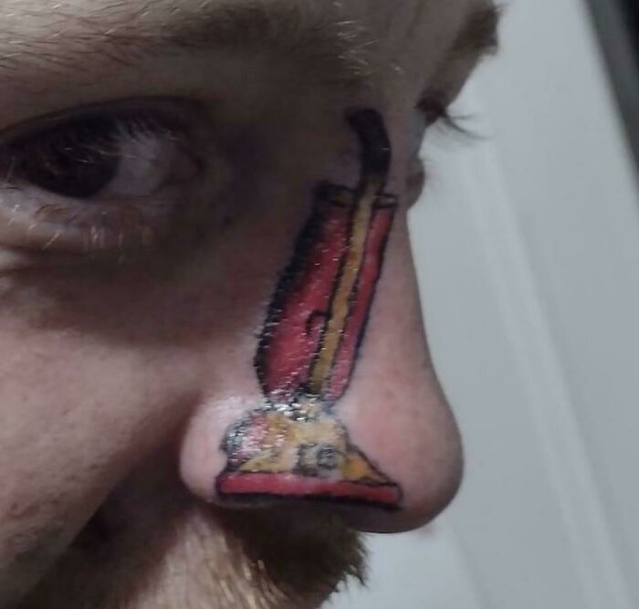 A tattoo of a red vacuum cleaner on a person's nose, illustrating an unconventional tattoo choice.