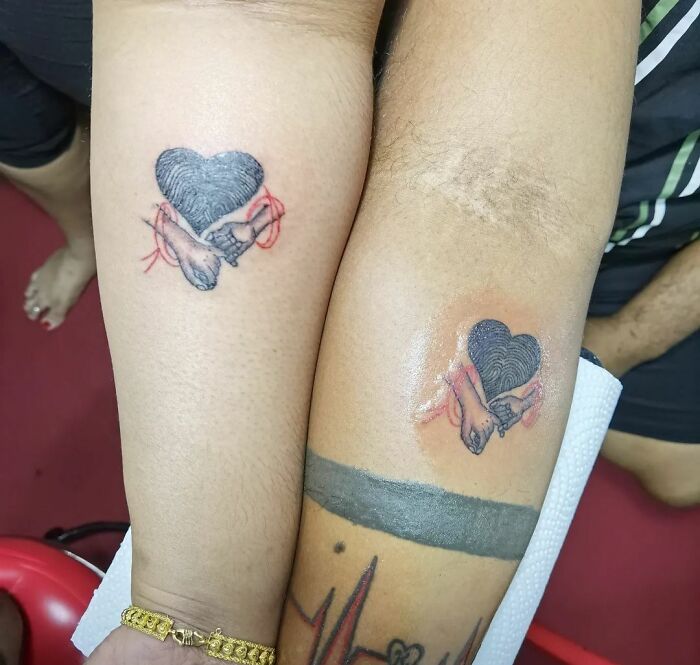 Matching tattoos of hearts and hands on two arms, symbolizing a special bond between loved ones.