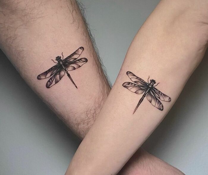 Matching dragonfly tattoos on forearms, symbolizing connection among couples or special people in your life.