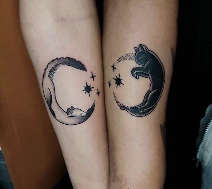 Matching tattoos of a black and white yin-yang cat design on arms, perfect for couples or special people.