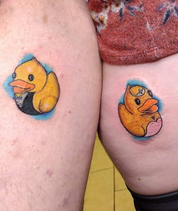 Matching tattoos of cartoon ducks on two people's arms, symbolizing close bonds.