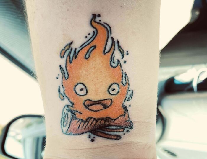 Cute flame character tattoo on an arm, illustrating pop culture design.