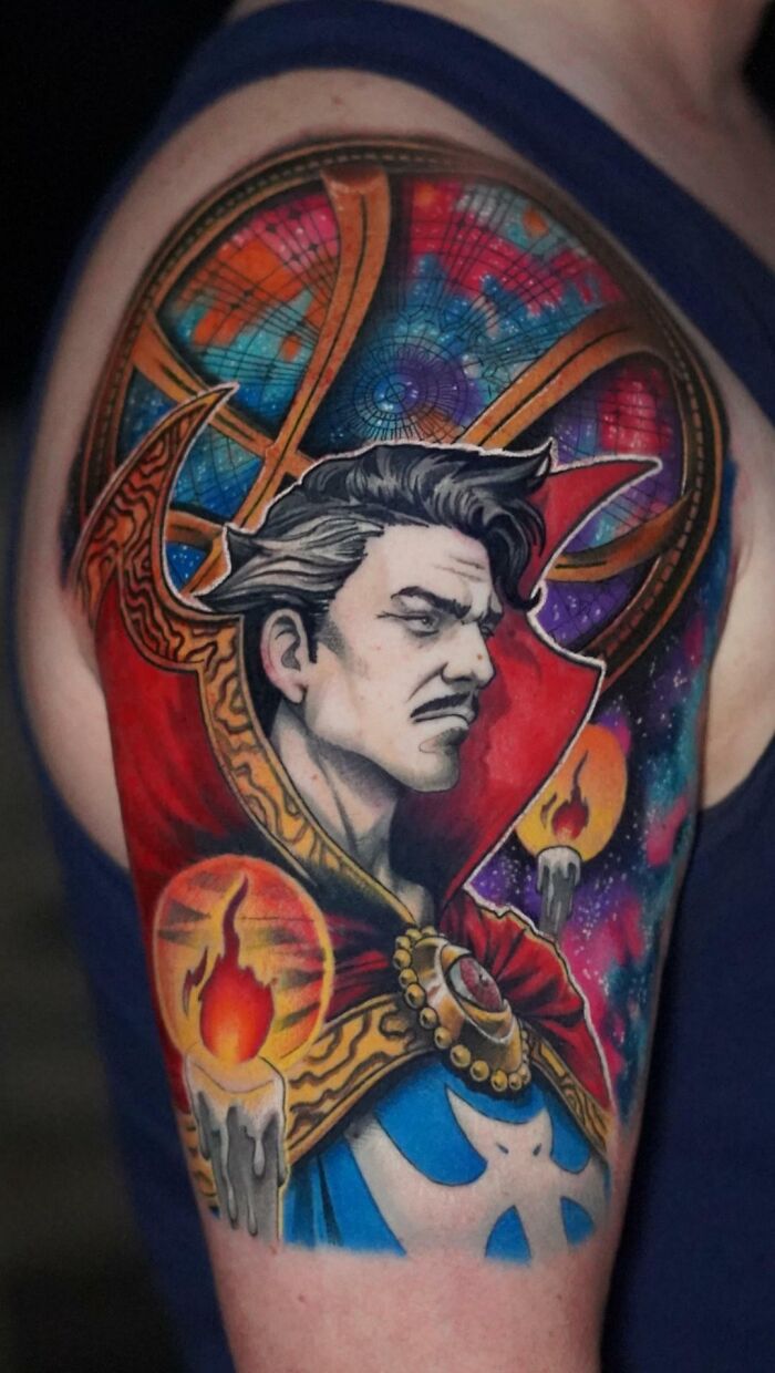 Vibrant pop culture tattoo of a mystical character with candles and cosmic background on an upper arm.