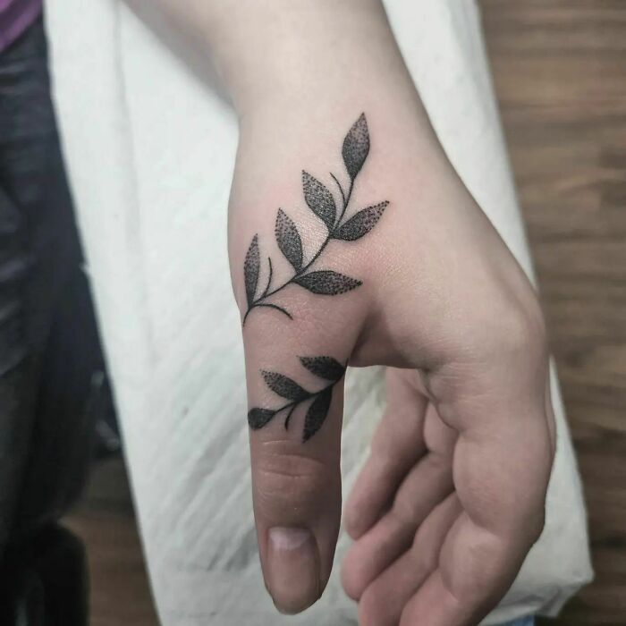 Leaf design small hand tattoo on a person's thumb and wrist.