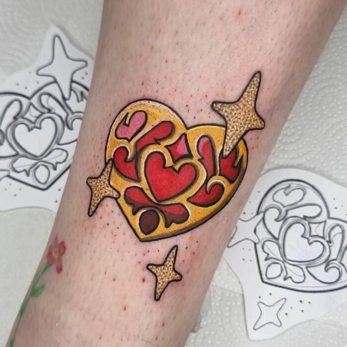 Colorful heart and stars pop culture tattoo on forearm with decorative design.
