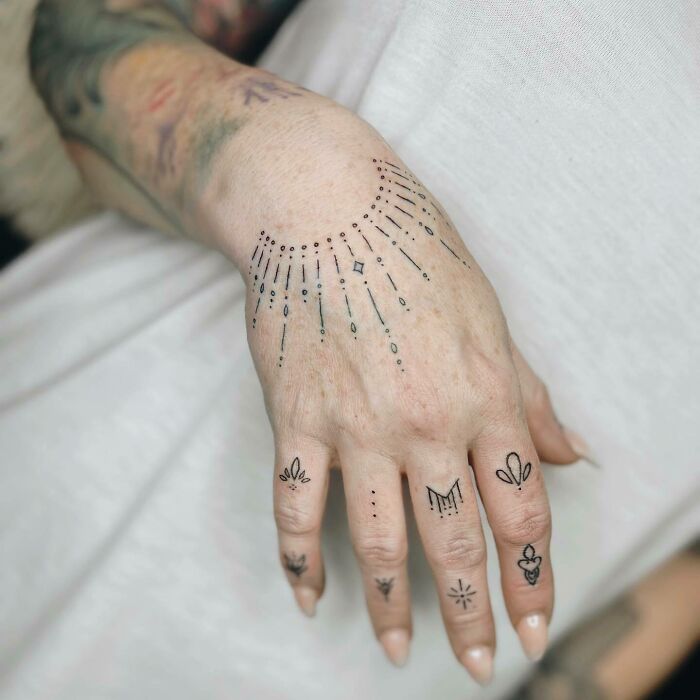 Small hand tattoos featuring intricate designs and patterns on fingers and back of the hand.