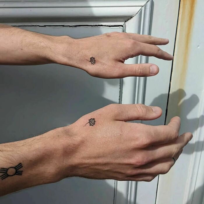 Small hand tattoos of roses and geometric patterns on a person's hands near a door.