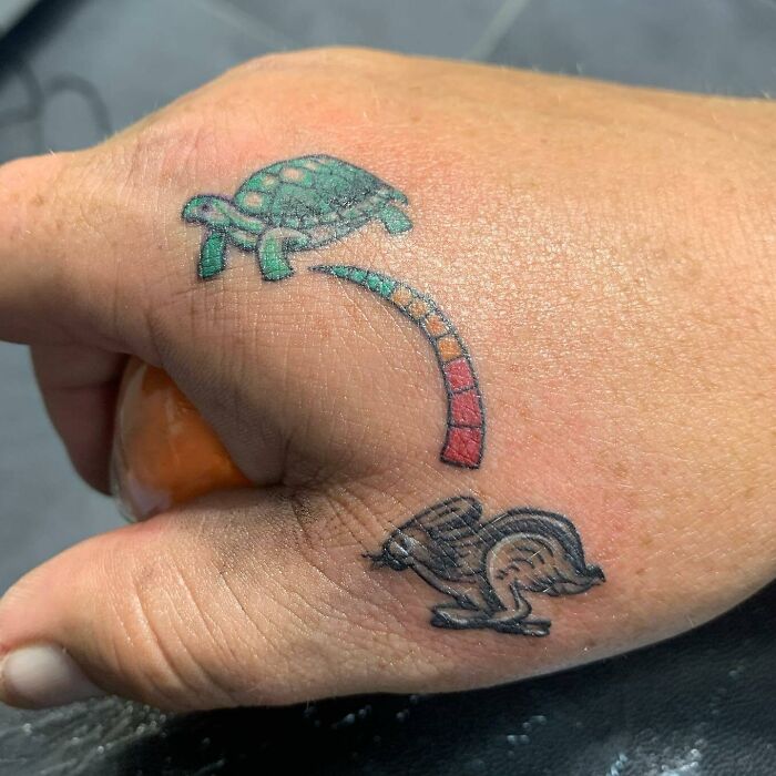 Hand showcasing small tattoos of a turtle and hare, symbolizing the classic race in vivid colors.