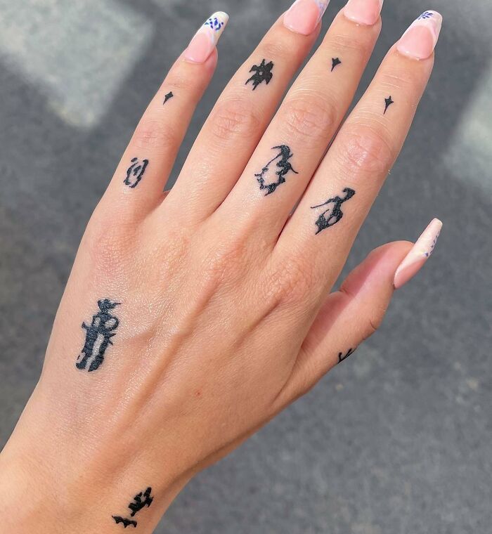Close-up of a hand with multiple small tattoos featuring abstract designs.