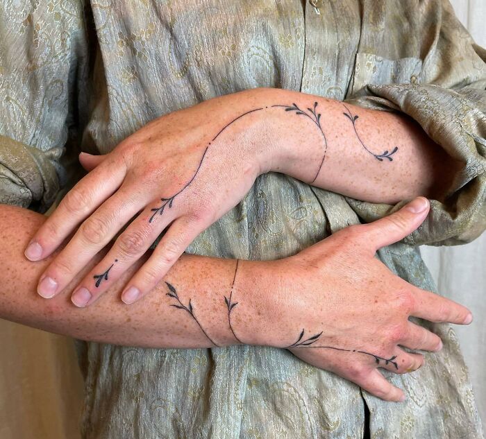 Delicate leafy small hand tattoo design on forearm and hand.