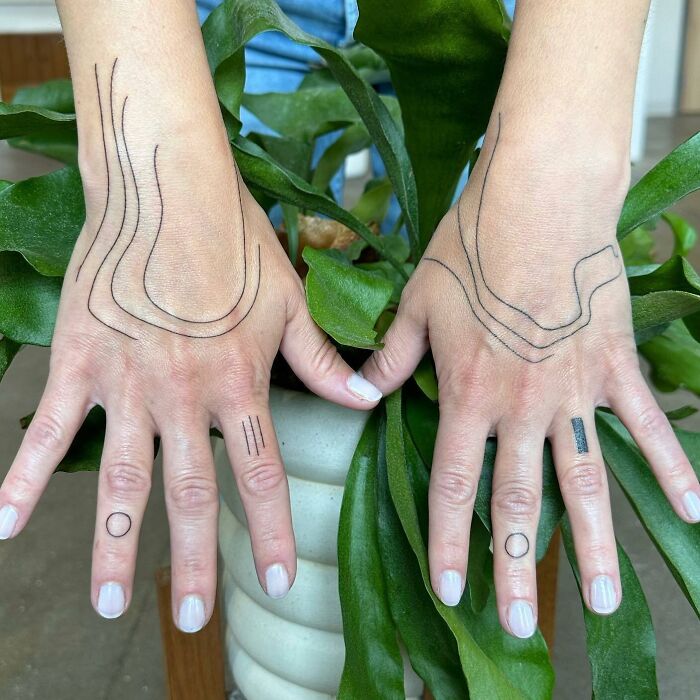 Small hand tattoos featuring minimalist line designs on fingers and hands.