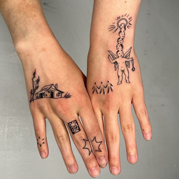 Small hand tattoos featuring a house, abstract designs, and a figure with wings on both hands.