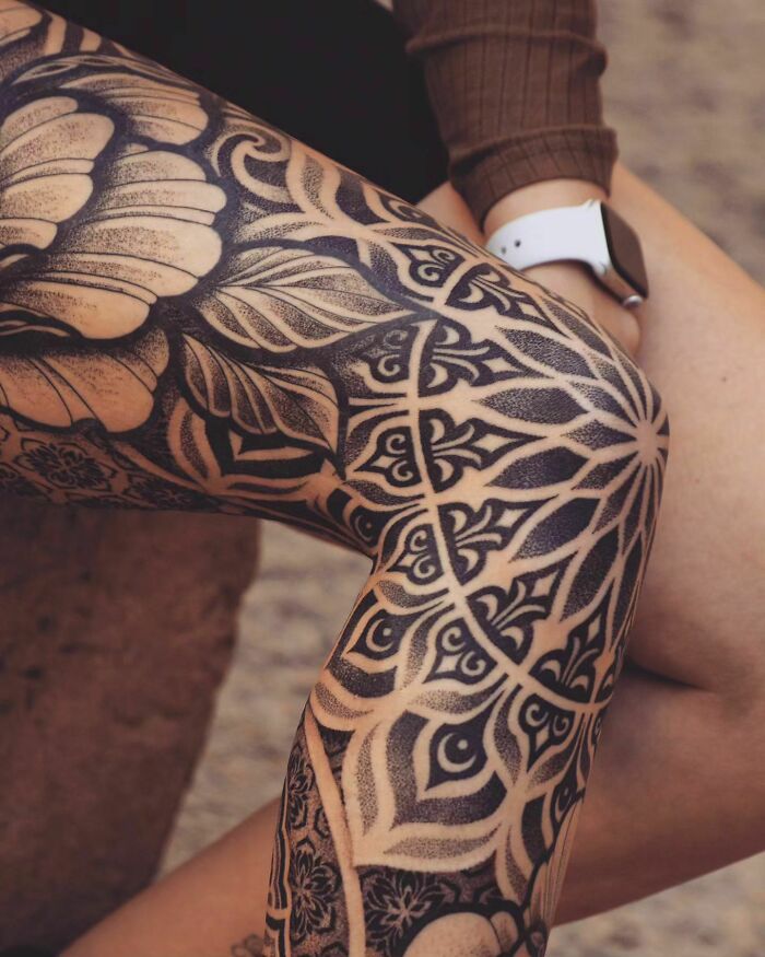Intricate geometric knee tattoos with bold black ink and floral patterns on legs.