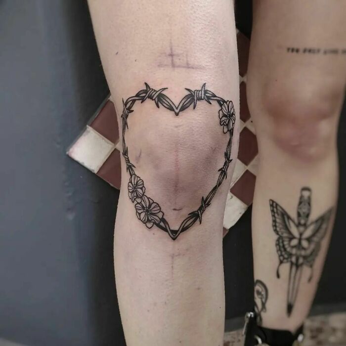Heart-shaped knee tattoo with floral design, making a bold statement.
