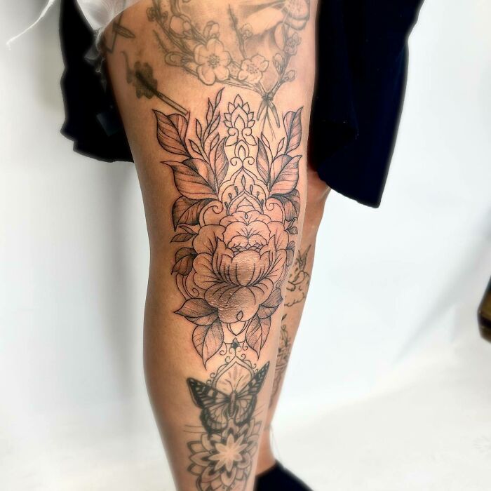 Floral and butterfly knee tattoo design showcasing intricate line work and detailed shading.