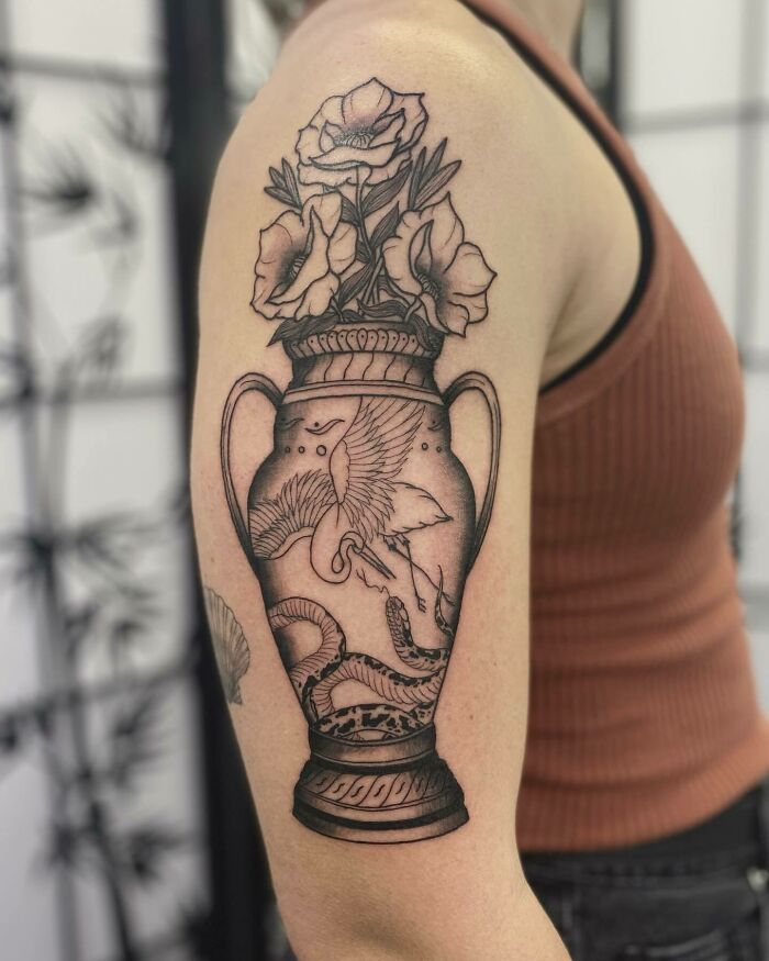 Flower tattoo with elegant vase design on upper arm, showcasing detailed floral art.