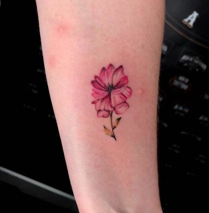 Pink flower tattoo on forearm, showcasing elegance and beauty.
