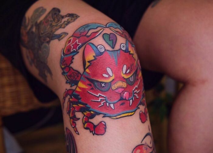 Colorful cat knee tattoo design with vibrant patterns and bold shapes.