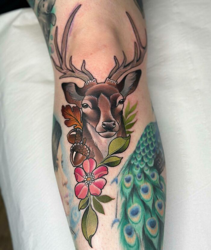 Deer and floral knee tattoo design featuring vibrant peacock feathers.