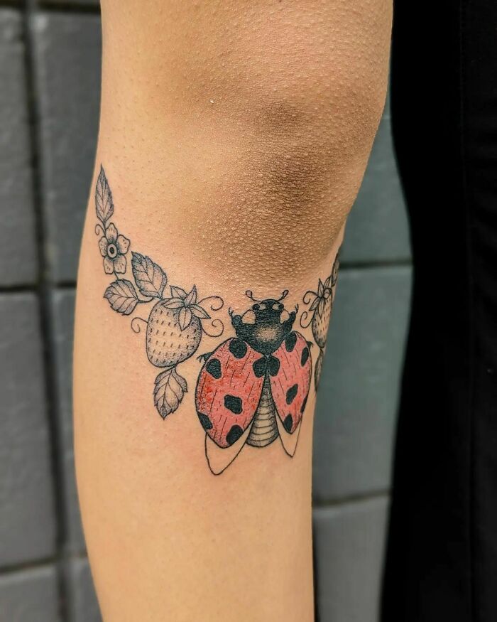 Ladybug and berry knee tattoo design, showcasing vibrant ink and detailed artistry.