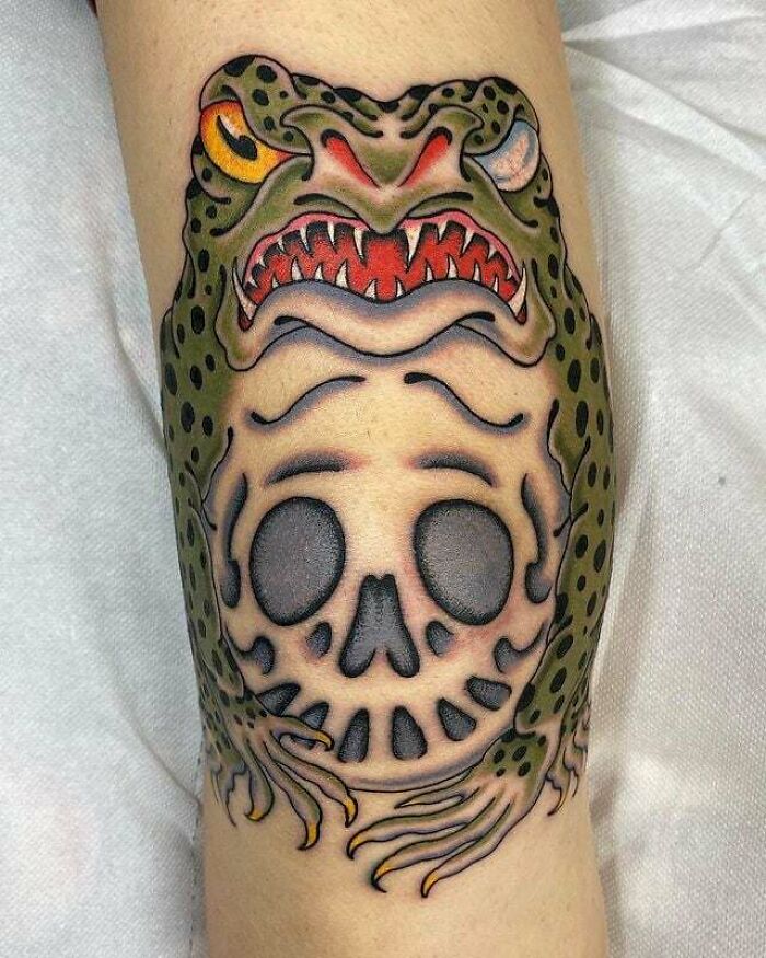 Knee tattoo design featuring a fierce green toad with a skull motif, showcasing bold and vibrant artistry.