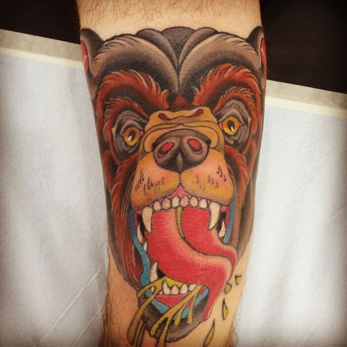 Vibrant knee tattoo design featuring a colorful, roaring bear's face with an extended tongue.