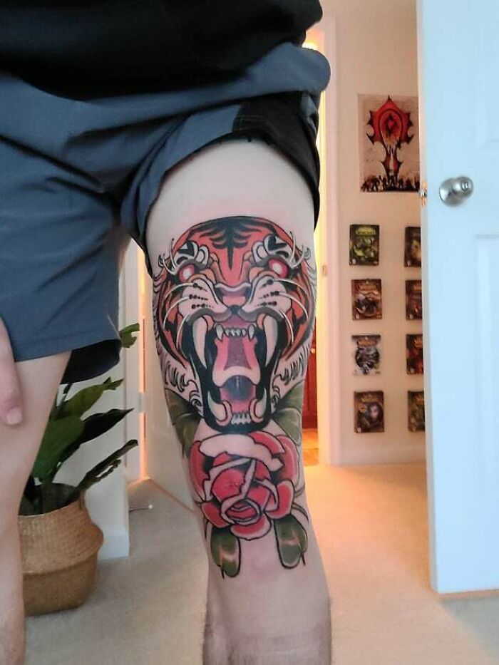 Tiger and rose knee tattoo design, featuring bold colors and intricate details, displayed in a well-lit room.