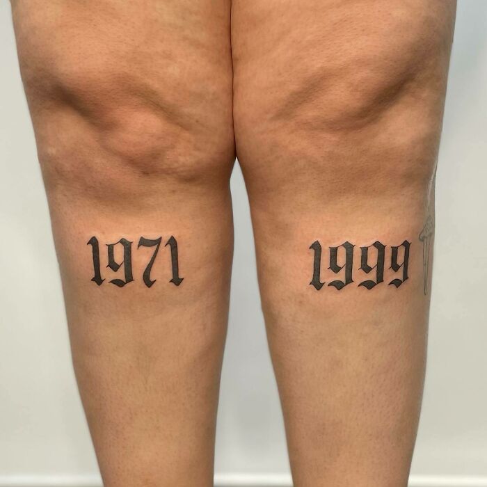 Knee tattoos featuring the years 1971 and 1999 in bold, black lettering.
