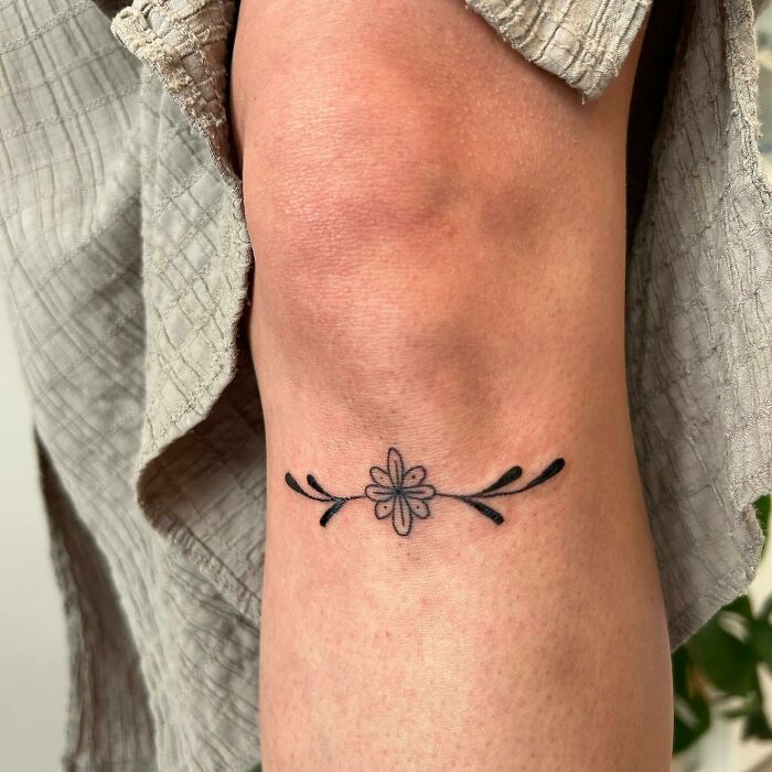 Floral knee tattoo design featuring a simple flower and leaves, perfect for making a statement.