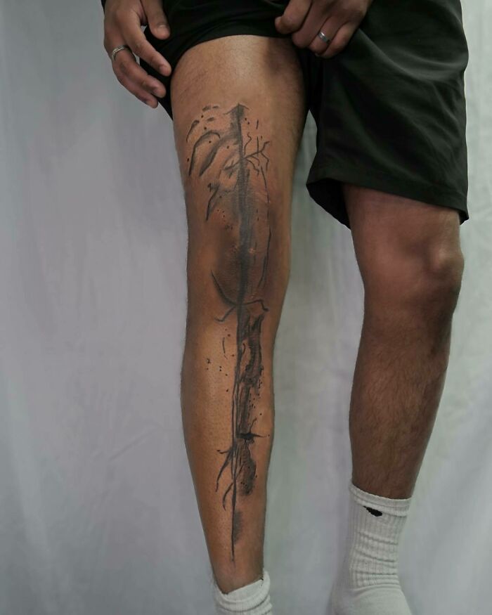 Abstract knee tattoo design on a person's leg, black ink with geometric elements.