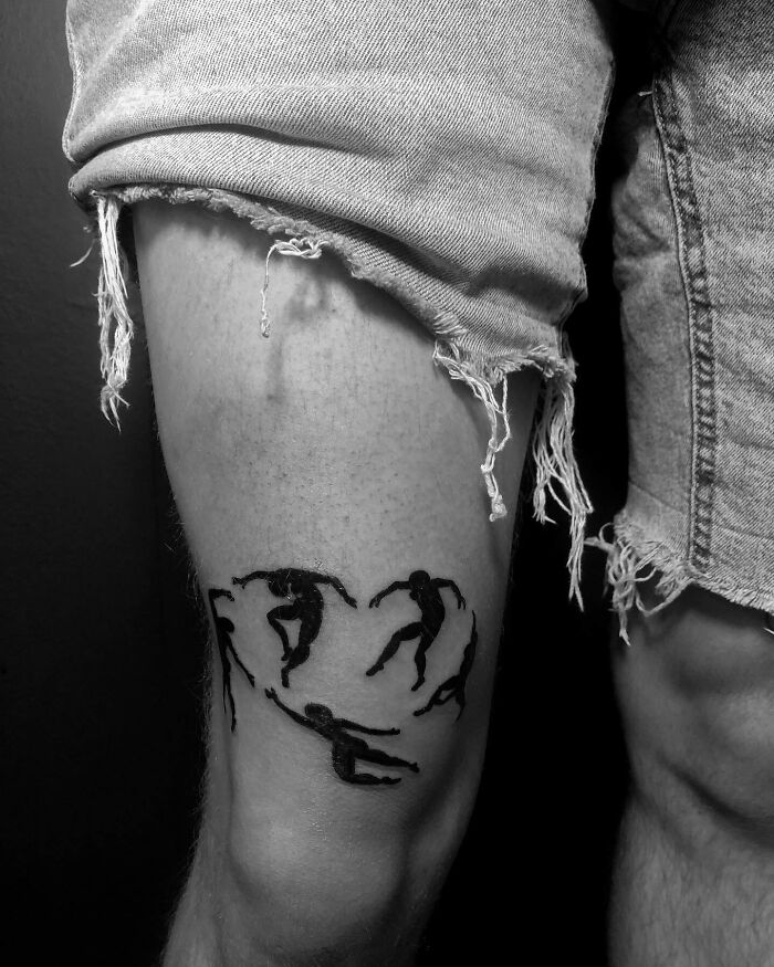 A person with shorts showing artistic knee tattoo featuring dynamic figures.