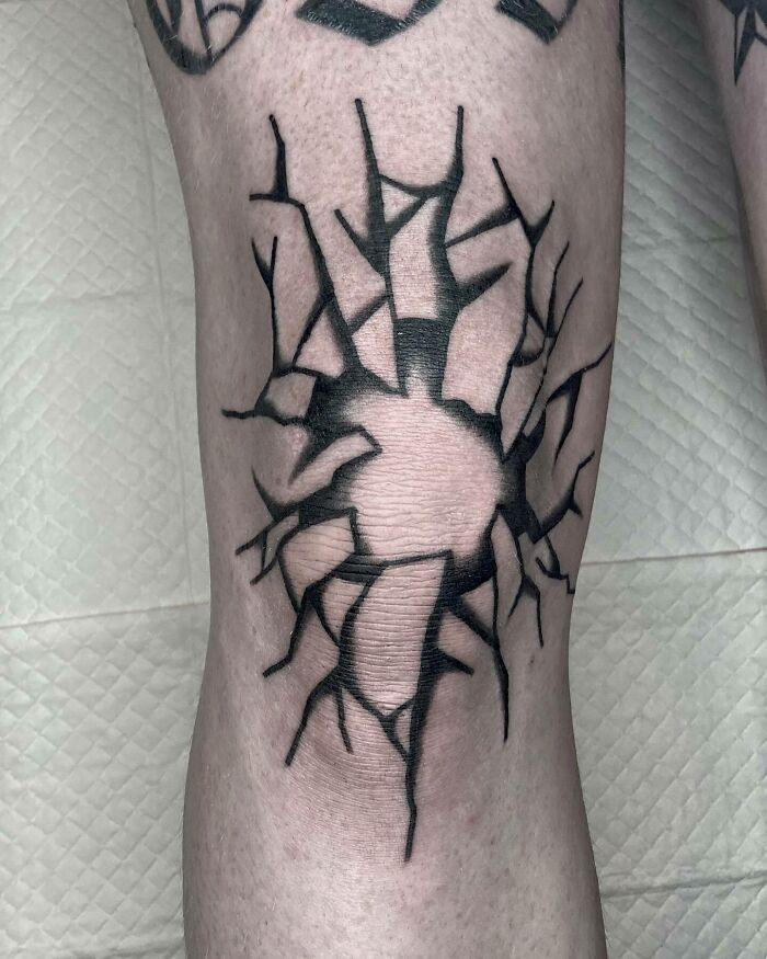 Black c*****d design knee tattoo making a bold statement.