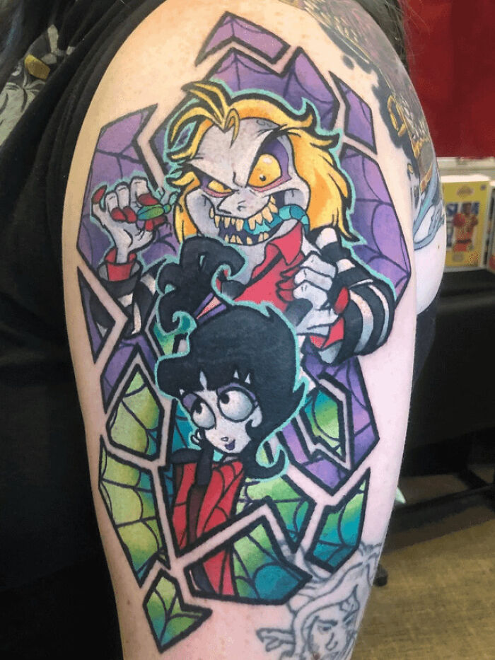 Colorful '90s tattoo featuring cartoon characters with geometric patterns on an arm.