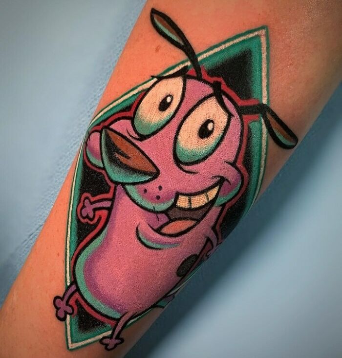 '90s tattoo of a cartoon dog in vibrant colors on an arm.