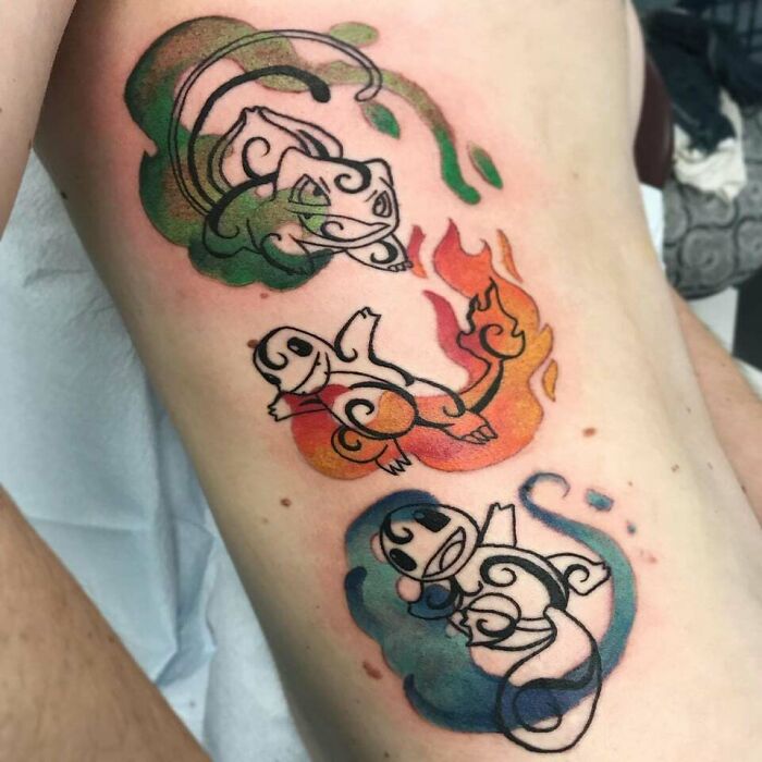 ‘90s tattoos of three stylized cartoon creatures in green, red, and blue flames on skin.