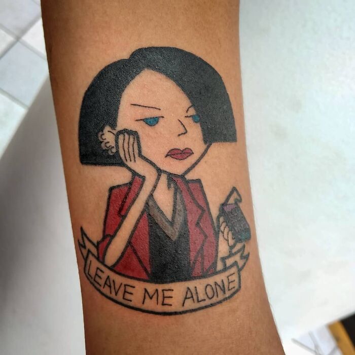 '90s tattoo depicting a cartoon character with a phone and the text "Leave Me Alone."
