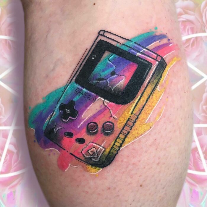 '90s tattoo of a Game Boy with watercolor effect on skin.