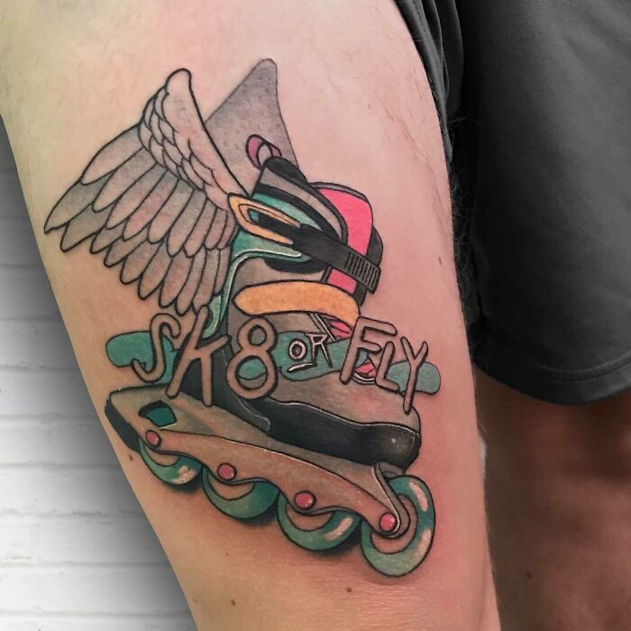 '90s tattoo of a winged rollerblade with "Sk8 or Fly" text on a thigh.