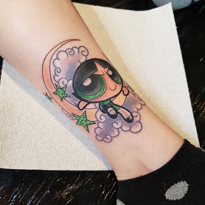 '90s tattoo featuring a cartoon character with stars and a crescent moon.