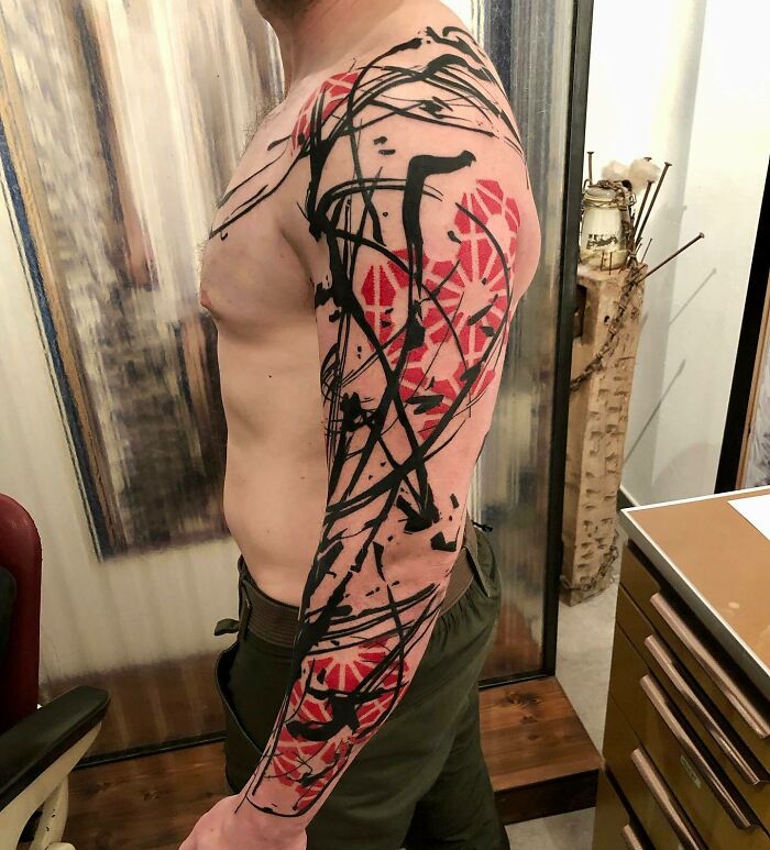 Side view of a person showcasing a striking full-sleeve Trash Polka tattoo design.