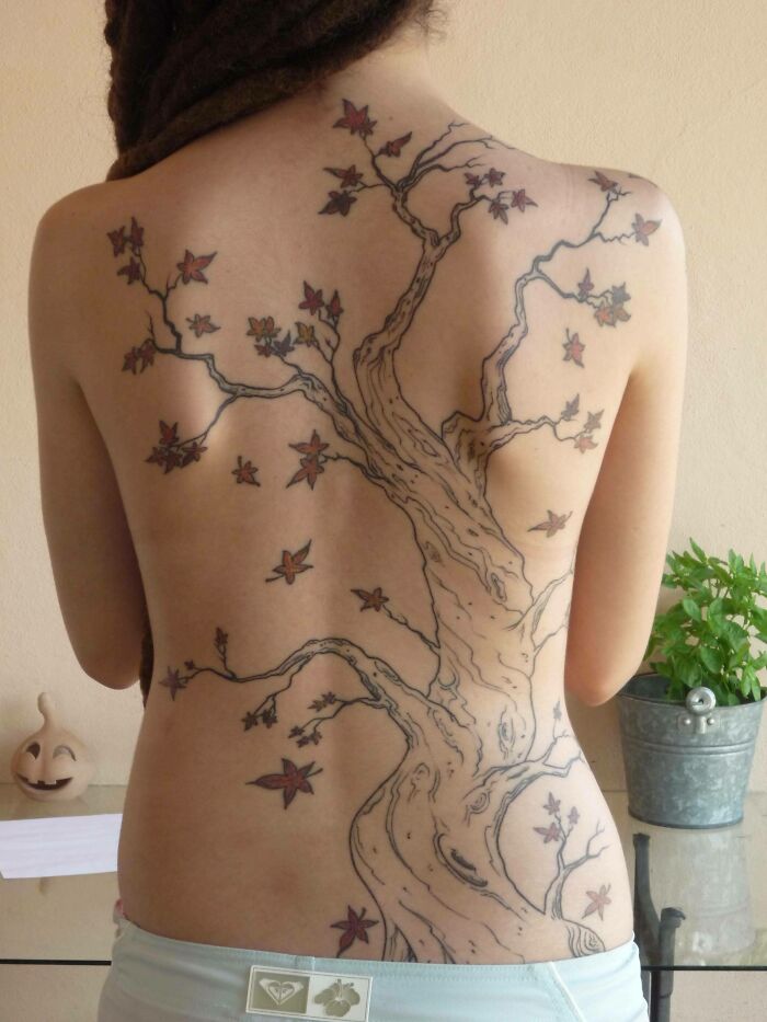 Back tattoo of a majestic tree with branches and leaves spread across the entire back, celebrating the wonders of nature.