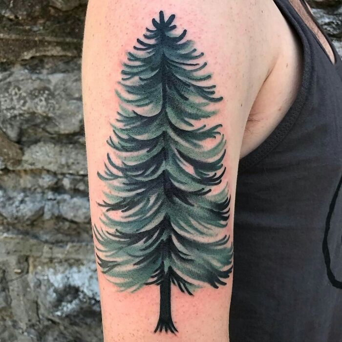 Tree tattoo on upper arm, showcasing nature's beauty with intricate green and black foliage.