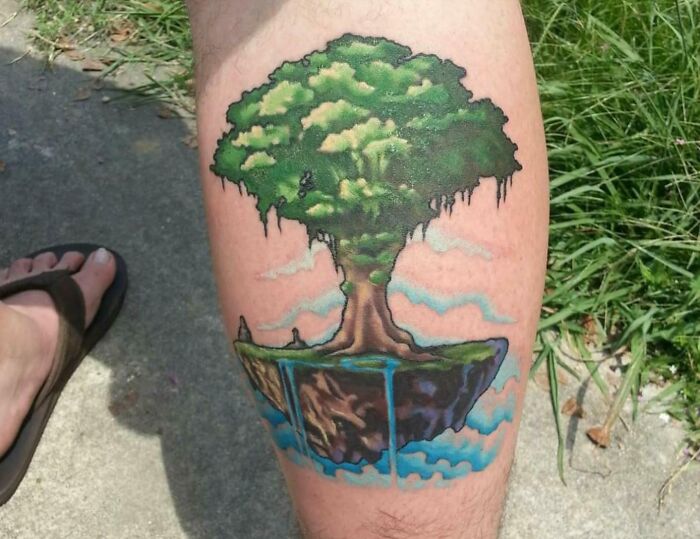 Tree tattoo on calf depicting a floating island with a lush tree and cascading water.
