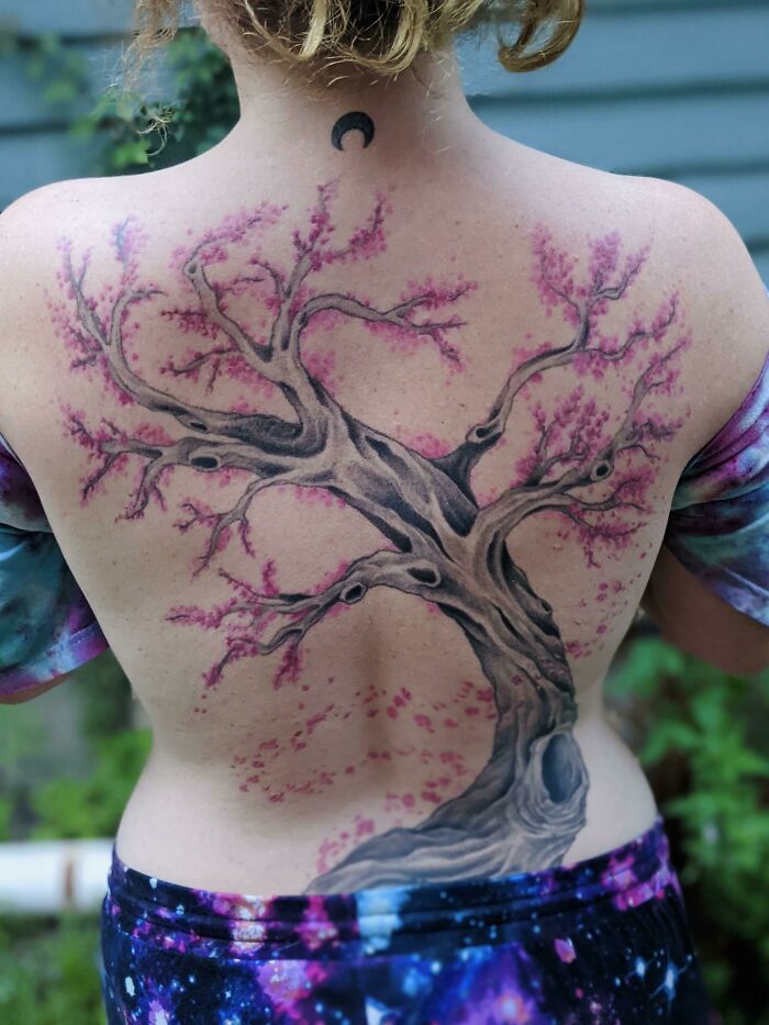 Back tattoo of a majestic tree with pink blossoms, celebrating the wonders of nature.